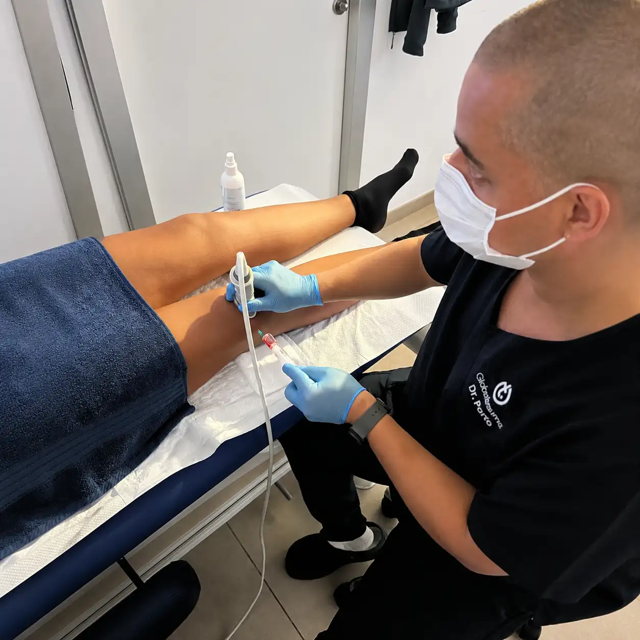 Especialista aplicando terapia regenerativa con agujas guiada por ecografía en la rodilla de un paciente en una clínica de Palma de Mallorca.